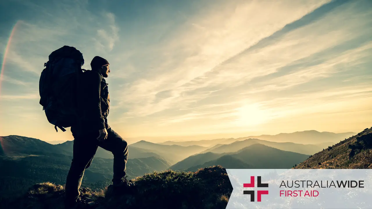 Male hiker standing on a mountain overlooking the sunset